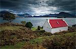 Scotland, Wester Ross. A brightly coloured cottage beside Loch Shieldaig on a gloomy day.