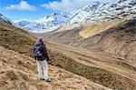 Scotland, Highland, Glencoe. Hiker looking at the view of snow covered hills. MR.