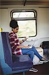 Full length of young woman using laptop while sitting in train