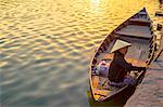 Vietnamese woman in a boat on the Thu Bon River at sunset, Hoi An, Quang Nam Province, Vietnam