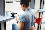 Woman using mobile phone while siting at restaurant