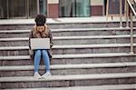 Full length of woman using laptop while sitting on steps