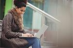 Smiling pretty woman using laptop while sitting on steps