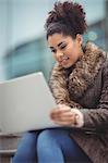 Low angle view of smart woman using laptop while sitting on steps