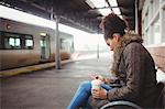 Woman using phone while sitting at railway station