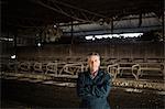Portrait of confident farm worker standing with arms crossed in barn