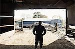 Rear view of farm worker standing in barn
