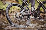 Low section of cyclist riding in stream at forest