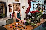 Female florist using laptop while talking on mobile phone in the flower shop