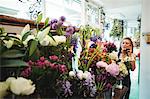 Female florist talking on mobile phone while arranging flowers in the flower shop