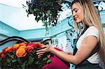 Female florist pouring water in flower vase at her flower shop