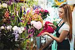 Female florist pouring water in flower vase at her flower shop