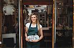 Portrait of female florist holding open signboard at her flower shop