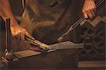 Blacksmith working on a heated iron rod in workshop