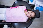 Smiling young patient sitting on dentist's chair at clinic