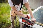 Carpenter cutting wooden frame from circular saw in lawn