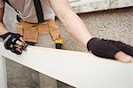 Mid section of carpenter leveling a wooden frame with block plane