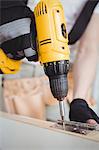 Carpenter tightening screw to hinges on a wooden door on a wooden door at home