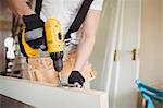 Carpenter tightening screw to hinges on a wooden door on a wooden door at home