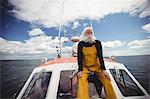 Thoughtful fisherman sitting on deck and looking at view