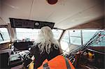 Rear view of fisherman driving fishing boat