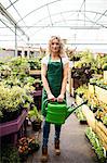 Portrait of female florist holding watering can in garden centre