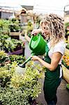 Female florist watering plants with watering can in garden centre