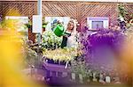 Female florist watering plants with watering can in garden centre