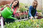 Female florist watering plant with watering can in garden center