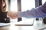 Businesswoman shaking hands with colleague in office