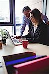 Businessman discussing with colleague over laptop in office