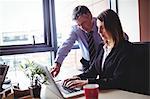 Businessman discussing with colleague over laptop in office