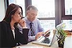 Businessman discussing with colleague over digital tablet in office