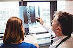 Doctor examining x-ray while nurse writing on clipboard at the hospital