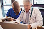 Doctor discussing with nurse over laptop at the hospital