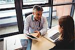 Doctor discussing with patient over digital tablet in the hospital