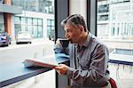 Man holding newspaper and having coffee in cafeteria