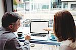 Man and woman discussing over laptop in the cafeteria