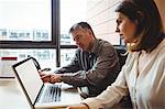 Woman discussing with colleague over laptop in the office