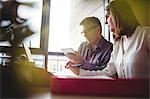 Man and woman discussing over digital tablet and laptop in the office