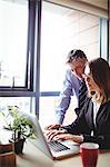 Businessman discussing with colleague over laptop in office