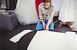 Female fashion designer cutting a white fabric in the studio