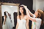 Woman trying on wedding dress in a studio with the assistance of creative designer