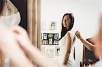 Woman trying on wedding dress in a studio with the assistance of creative designer