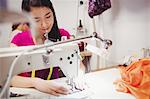 Female dressmaker sewing on the sewing machine in the studio