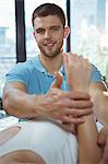 Male physiotherapist giving arms massage to female patient in clinic