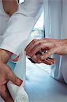 Male therapist putting bandage on female patient hand in clinic