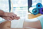 Male physiotherapist giving back massage to female patient in clinic