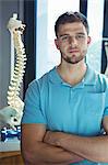 Portrait of male physiotherapist standing with arms crossed in the clinic