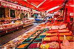 Red awnings covering bins of bulkfood and deli counter at the Ballaro Market in the historic center of Palermo in Sicily, Italy